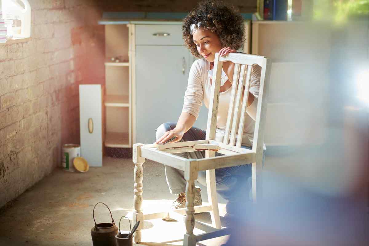 una ragazza scartavetra la sedia in legno