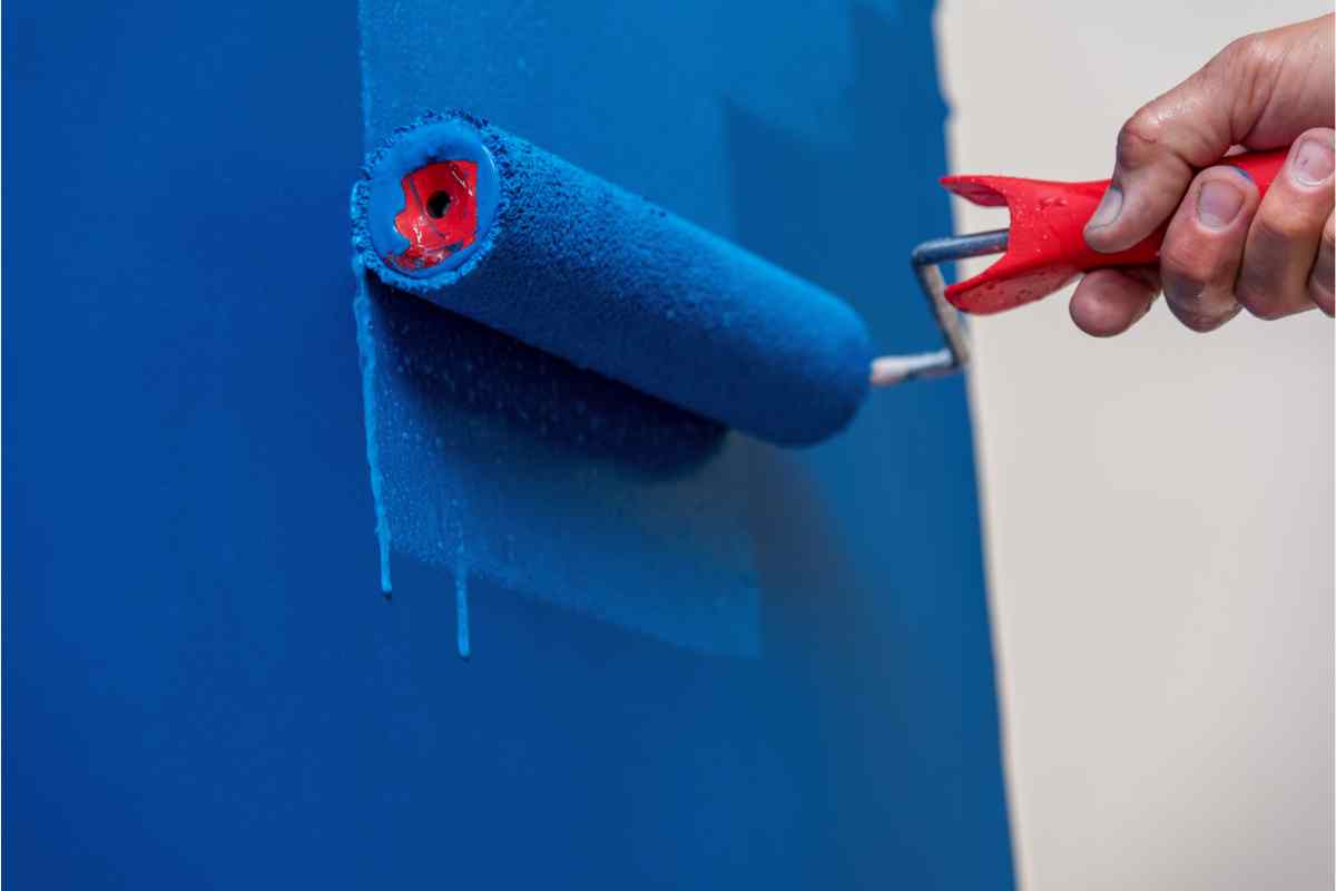 Verniciare pareti di casa fai da te, mano con rullo stende vernice blu