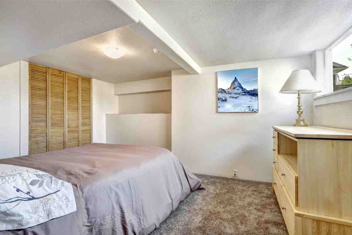 camera da letto con soffitto basso e quadro appeso 