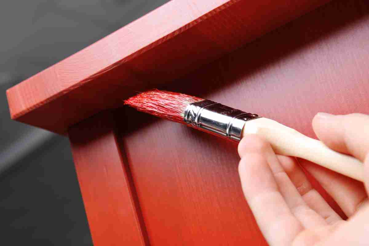 mano con pennello dipinge mobili Ikea di rosso