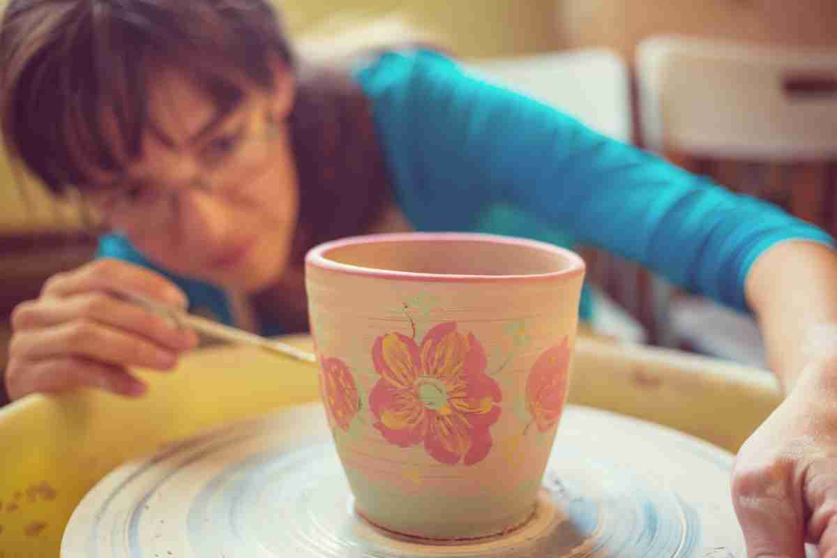 donna disegna su vaso dei fiori rosa
