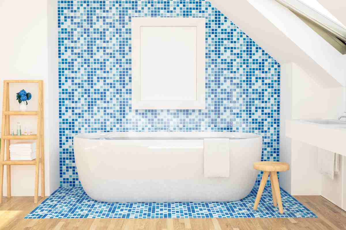 le pareti del bagno sono a mosaico e gli arredi in legno chiaro