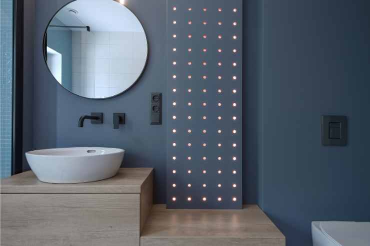 Bagno cieco con parete blu navy e luci led su parete che creano un design chic