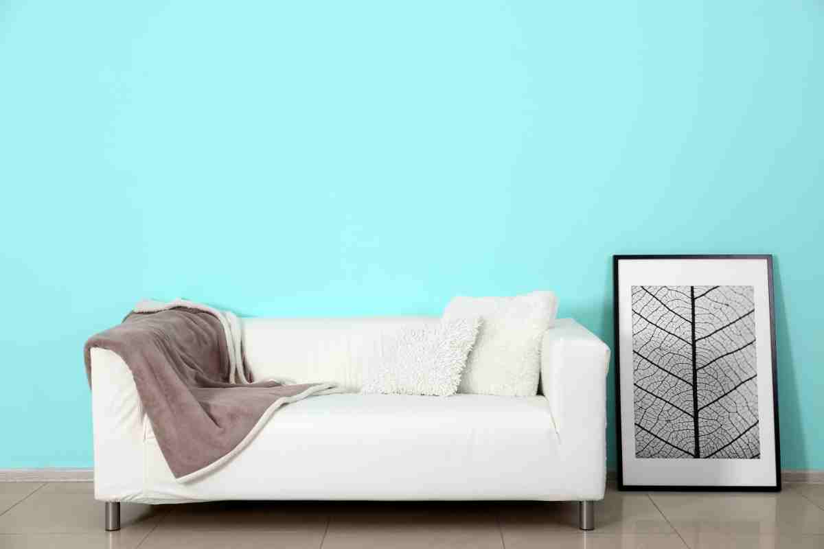 Pavimento grigio con divano bianco e parete blu