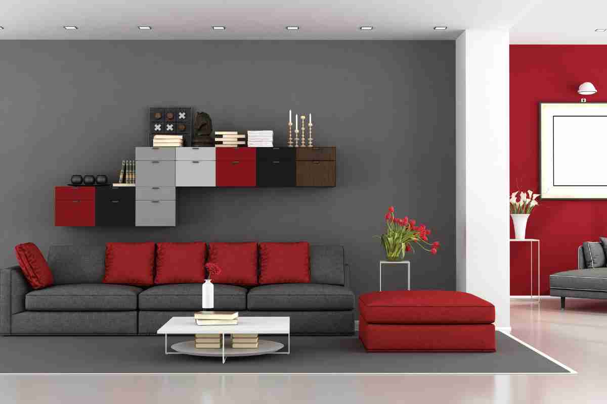 soggiorno con divano grigio e rosso e pareti di colore grigio