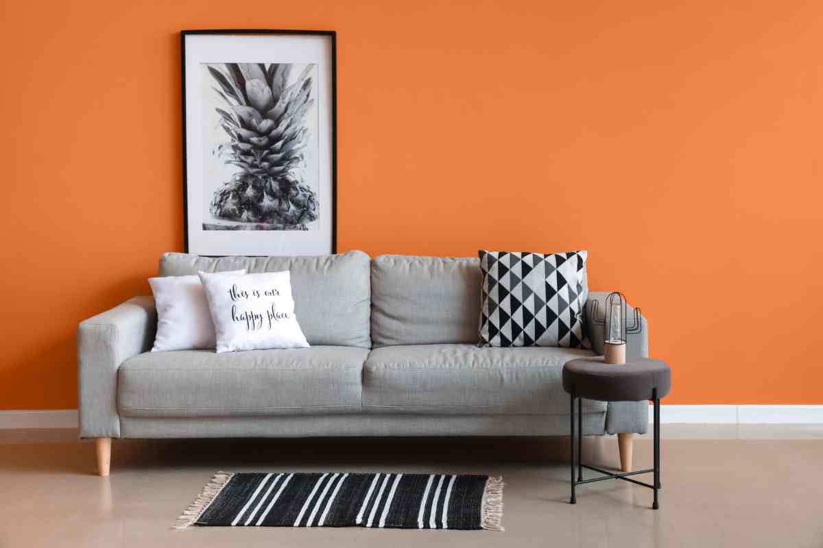 pareti arancioni e divano grigio chiaro 