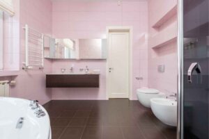 Bagno rosa con mobili in legno e sanitari bianchi