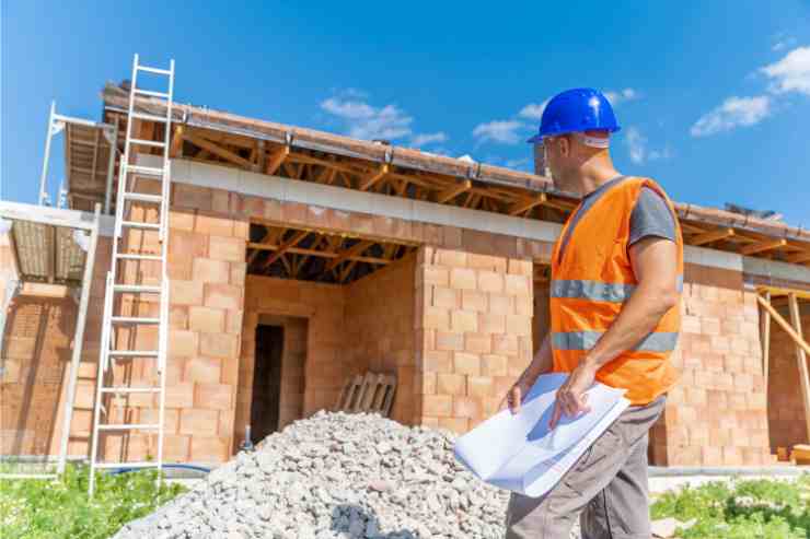 capocantiere controlla i lavori edili ad una casa con in mano documenti scia