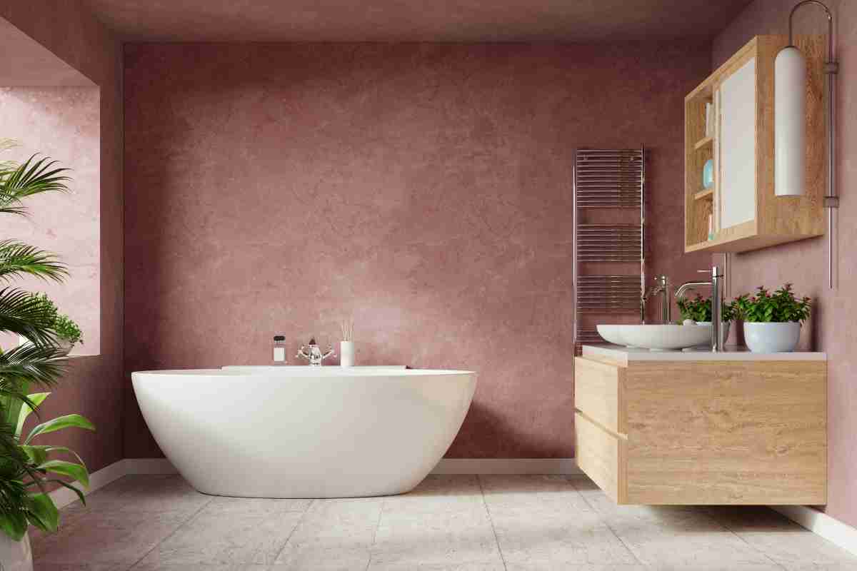 bagno con pareti rosa e mobili in legno chiaro