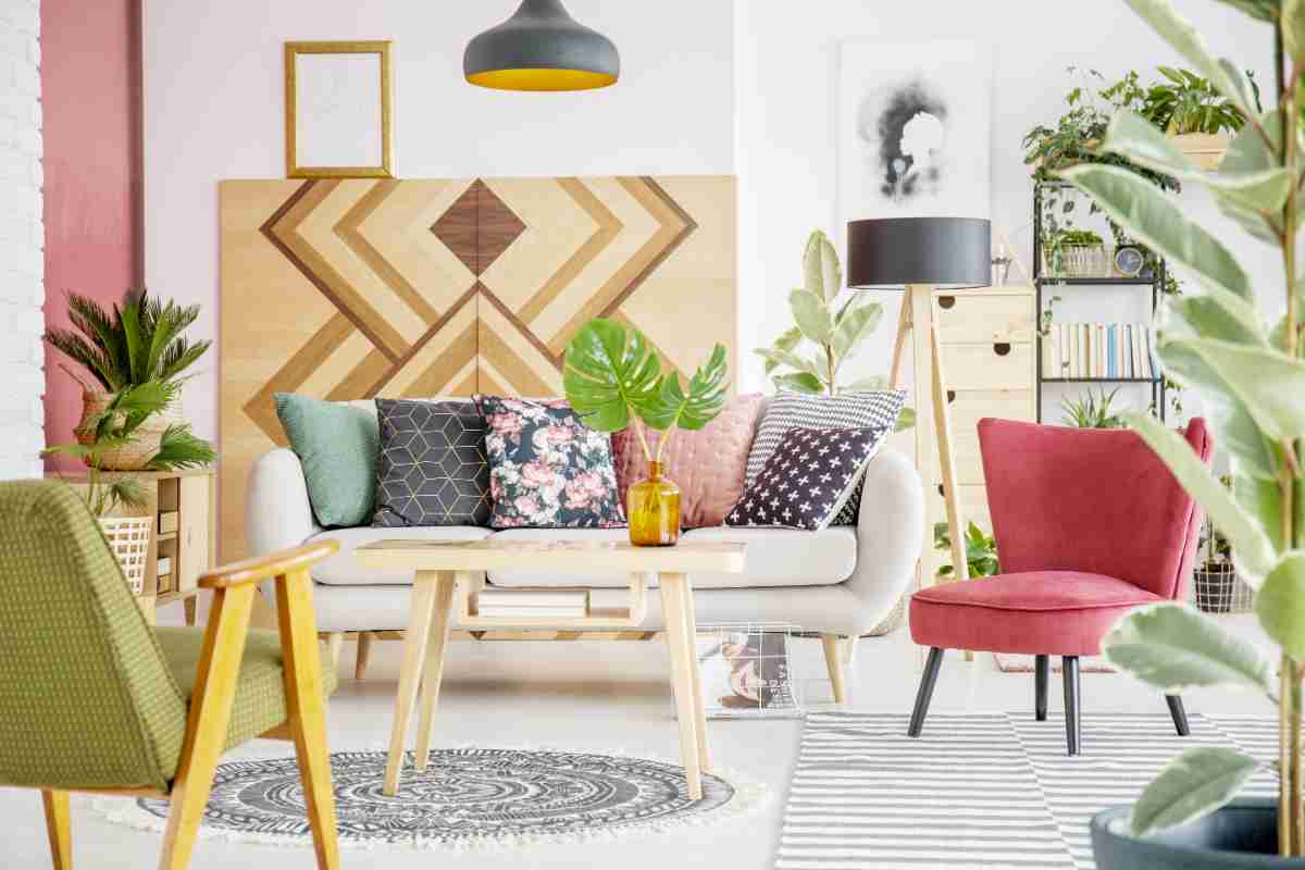 soggiorno con mobili in legno e tessuti da abbinare, cuscini decorati su divano bianco, poltrona rosa e sedia con braccioli blu