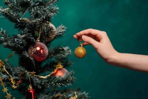 donna addobba l'albero con le palline di natale