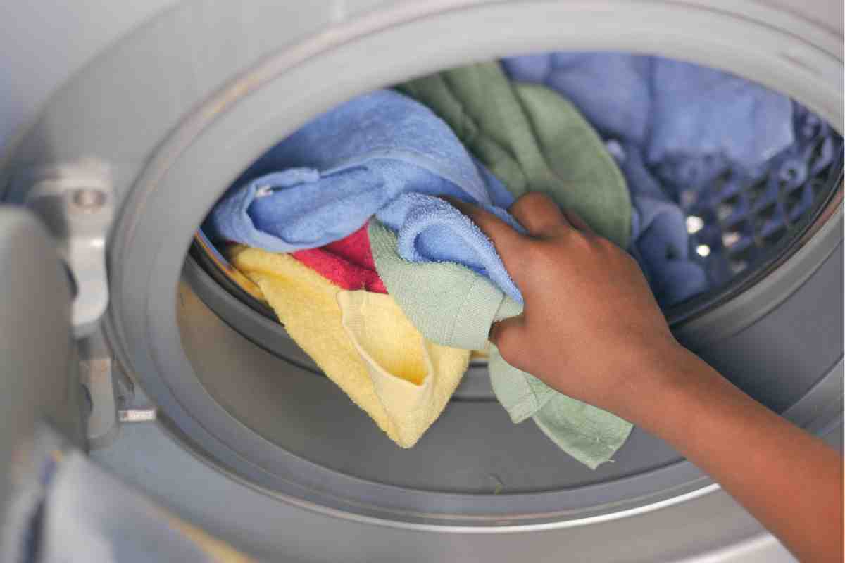 mano mette bucato in lavatrice