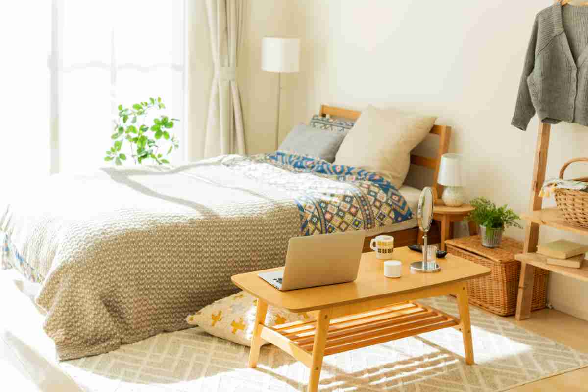 cameretta con le pareti di colore beige e rifiniture in verde, letto in legno, tappeto chiaro e tavolino basso