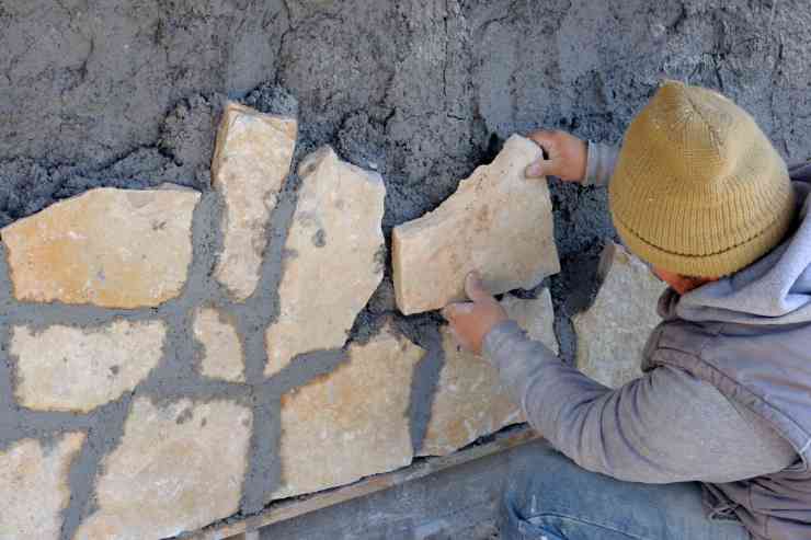 Uomo posiziona le pietre da incollare alla parete 