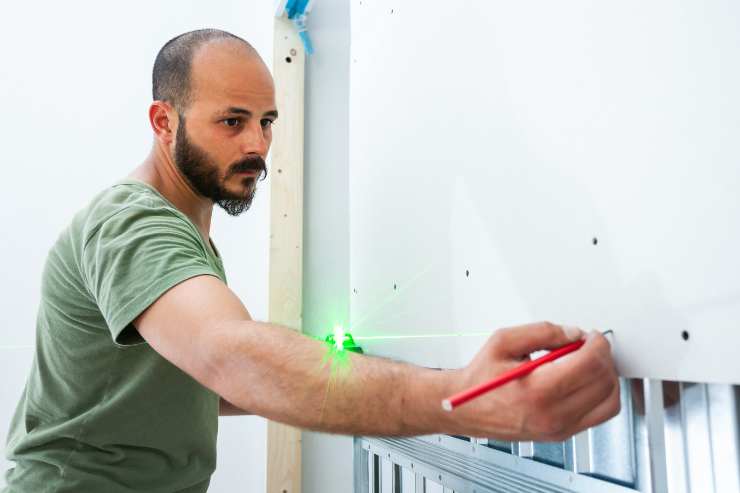 uomo con metro laser prende le misure 