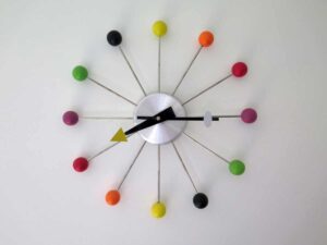 Orologio da parete moderno con raggi di metallo e palline colorate alle estremità