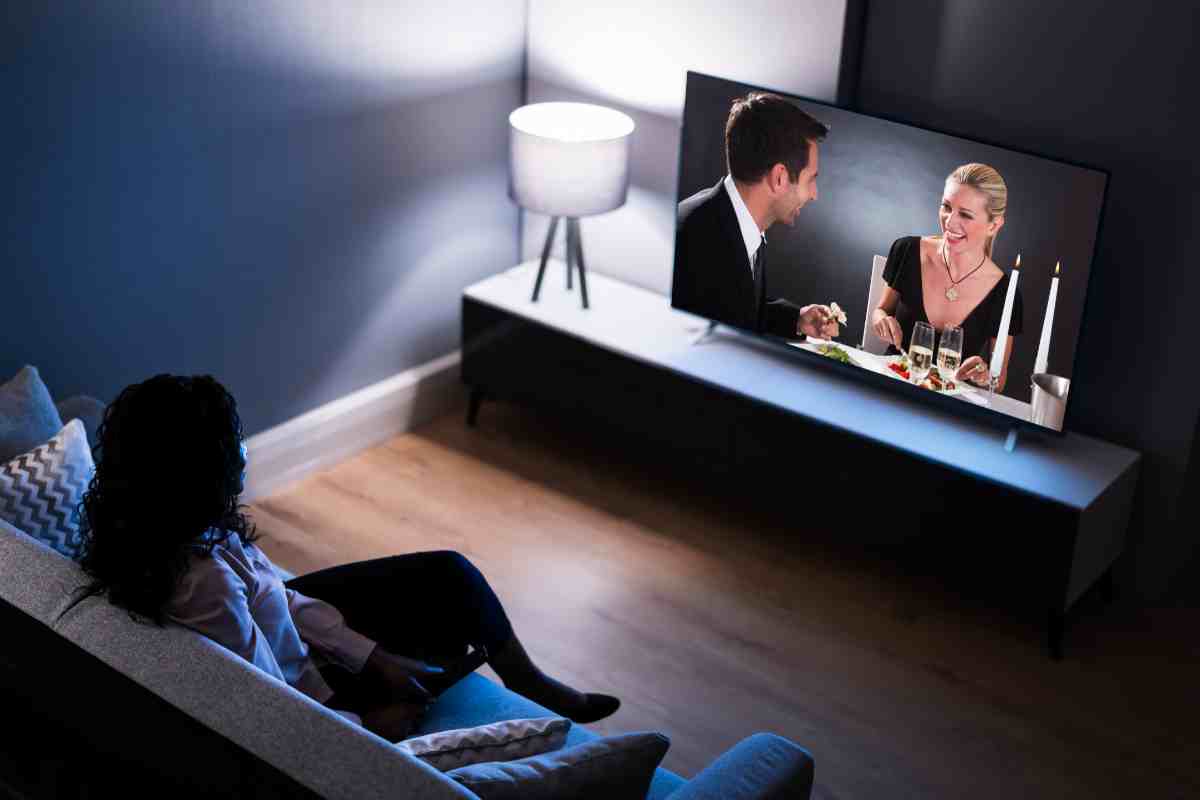 donna in salotto seduta sul divano davanti a una delle Migliori Smart tv