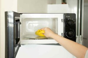 mano con un spugna dentro al forno a microonde