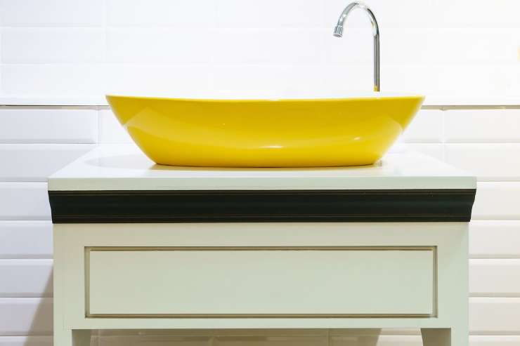 Lavabo da appoggio in ceramica giallo su mobile vintage