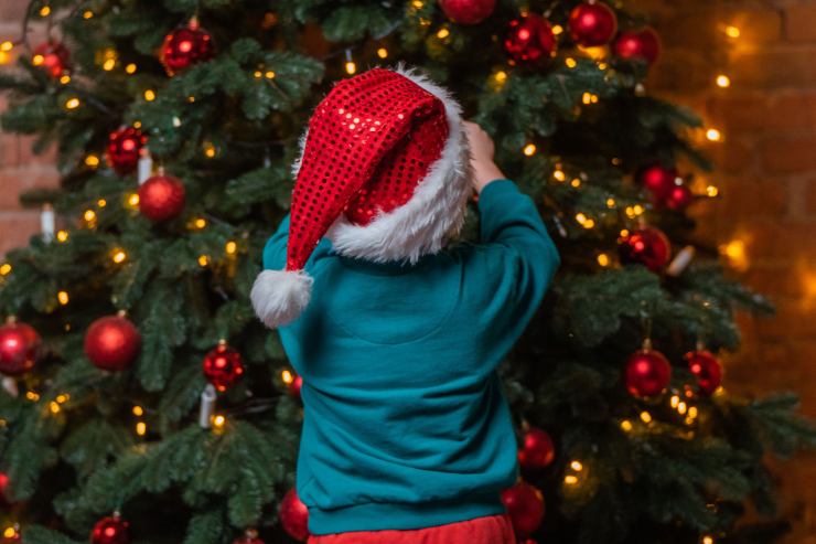 Bambino che addobba l'albero di natale