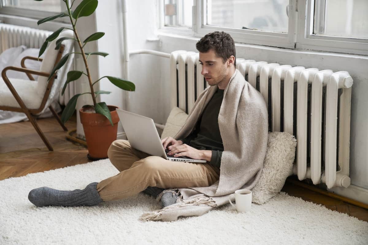 Uomo seduto accanto a un termosifone