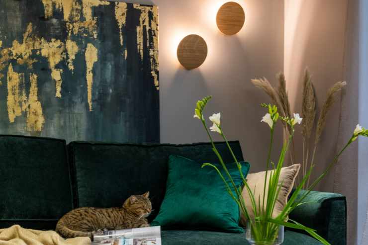 Illuminazione rilassante in soggiorno con divano di velluto verde e gatto